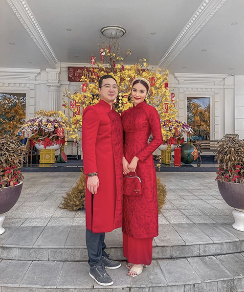 Lan Khuê diện áo dài đôi cùng chồng với tông đỏ rực rỡ tượng trưng cho may mắn, thành công và hạnh phúc.
